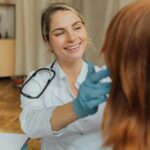A cheerful healthcare professional examining a patient indoors, promoting positive healthcare experiences.