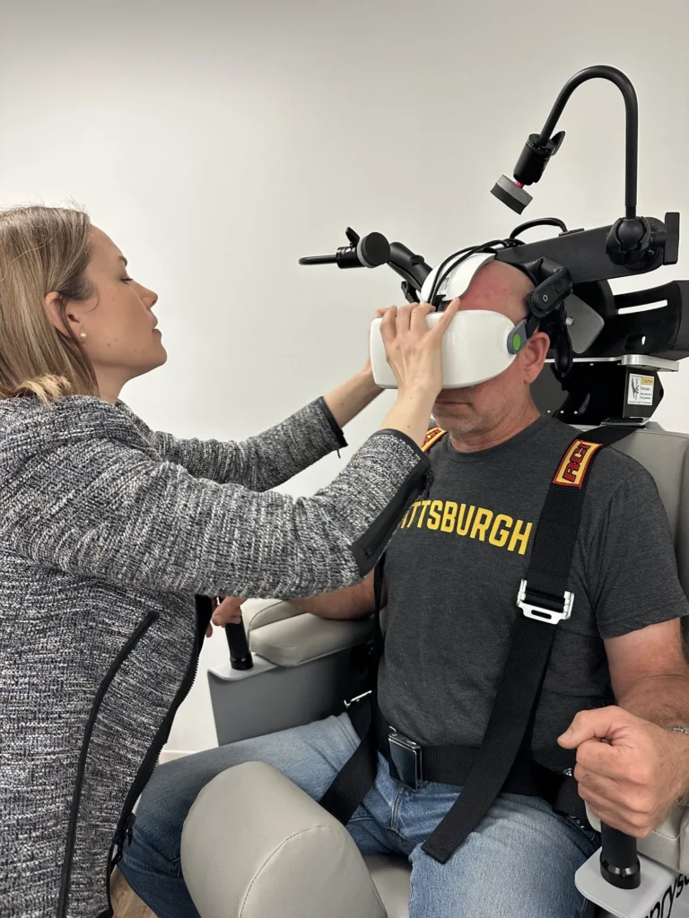 Clinician fitting video eye-tracking goggles on a patient seated in the rotary chair